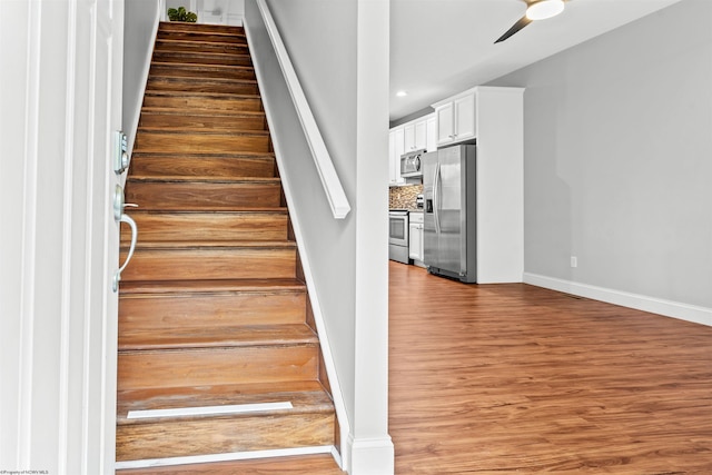 staircase featuring a ceiling fan, recessed lighting, baseboards, and wood finished floors