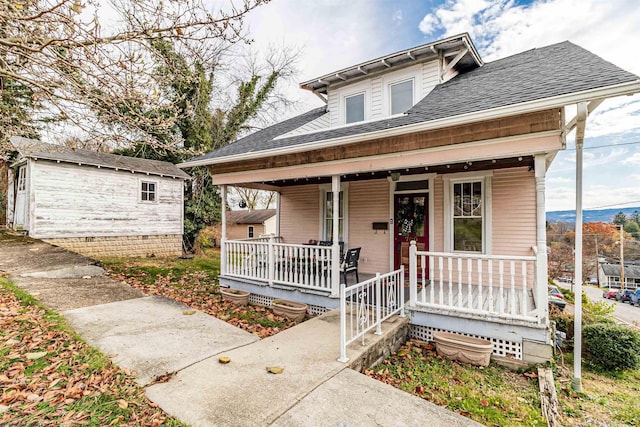 bungalow featuring a shingled roof, an outbuilding, and covered porch