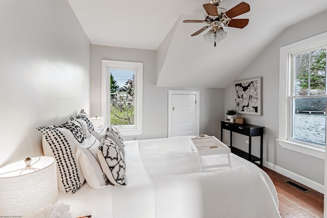 bedroom featuring ceiling fan, wood finished floors, visible vents, baseboards, and vaulted ceiling