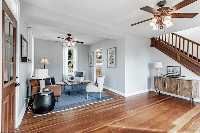 sitting room with stairs, ceiling fan, wood-type flooring, and baseboards