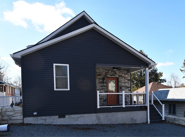 view of front of house with covered porch, stone siding, and crawl space