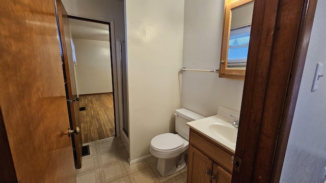 bathroom with tile patterned floors, toilet, vanity, baseboards, and walk in shower