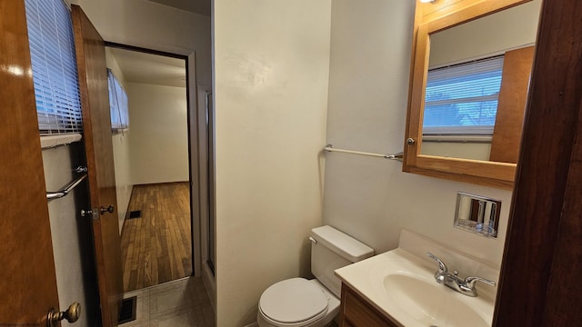 bathroom with toilet, wood finished floors, visible vents, vanity, and an enclosed shower