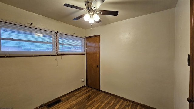 empty room featuring baseboards, dark wood-style flooring, visible vents, and a ceiling fan