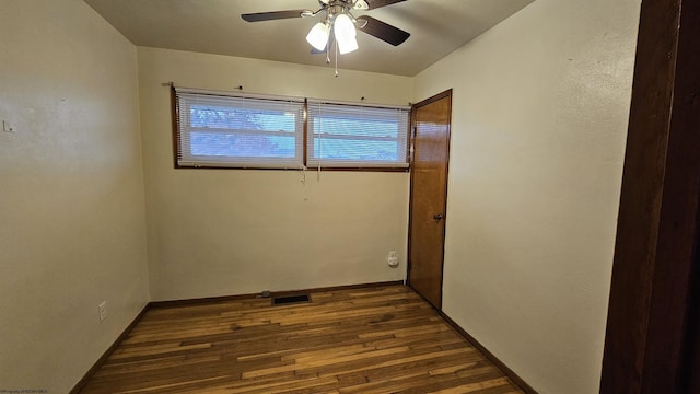 empty room with baseboards, ceiling fan, visible vents, and dark wood-type flooring