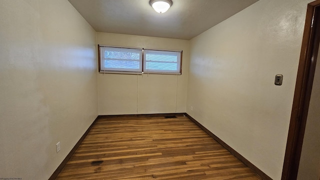 spare room featuring dark wood-style floors and baseboards