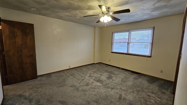 unfurnished room featuring dark colored carpet, a ceiling fan, and baseboards