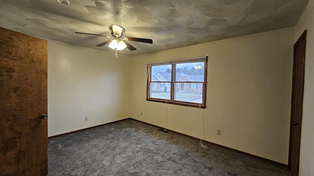 empty room featuring ceiling fan, dark colored carpet, and baseboards