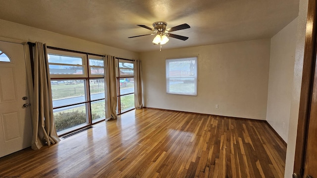 empty room with baseboards, visible vents, ceiling fan, and hardwood / wood-style floors