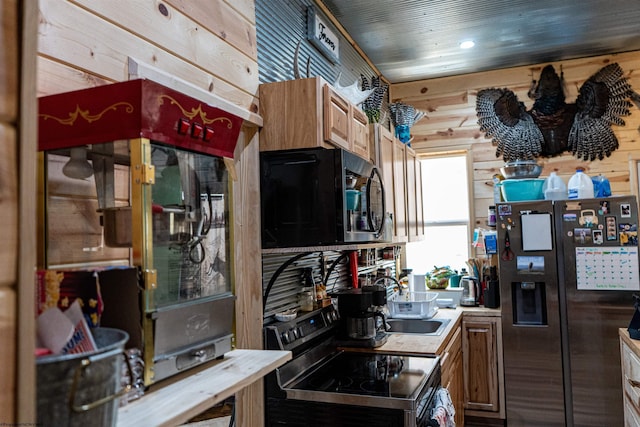 kitchen featuring wooden ceiling, wooden walls, stainless steel appliances, a sink, and light countertops