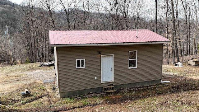 view of outdoor structure with entry steps and a wooded view