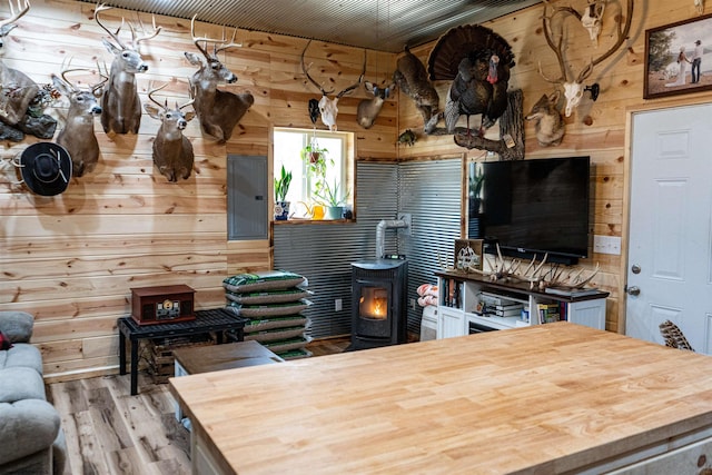 kitchen with light wood finished floors, butcher block counters, wood walls, and a wood stove