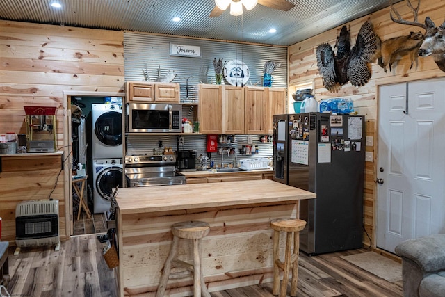 kitchen featuring stacked washer / dryer, wood counters, appliances with stainless steel finishes, heating unit, and a sink