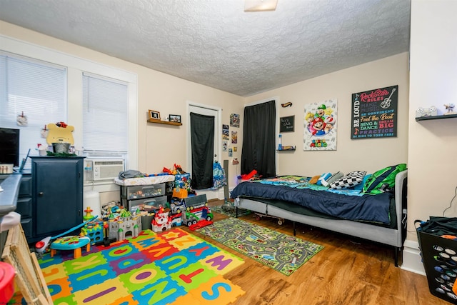 bedroom featuring a textured ceiling, cooling unit, and wood finished floors