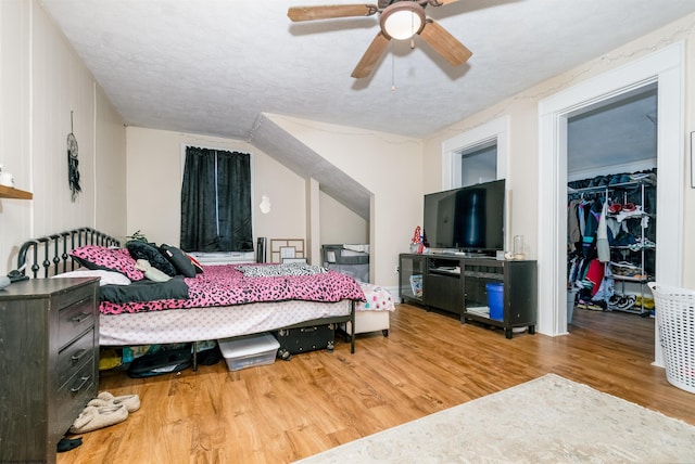 bedroom featuring a spacious closet, a textured ceiling, and wood finished floors