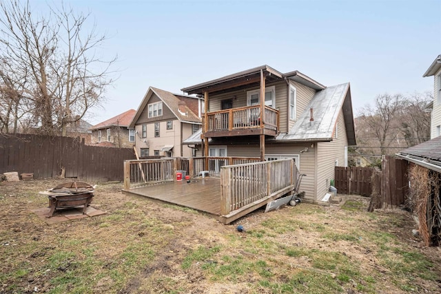 rear view of house featuring a fenced backyard, a fire pit, and a wooden deck