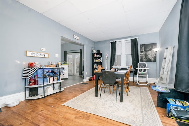 dining room with wood finished floors, a paneled ceiling, and baseboards