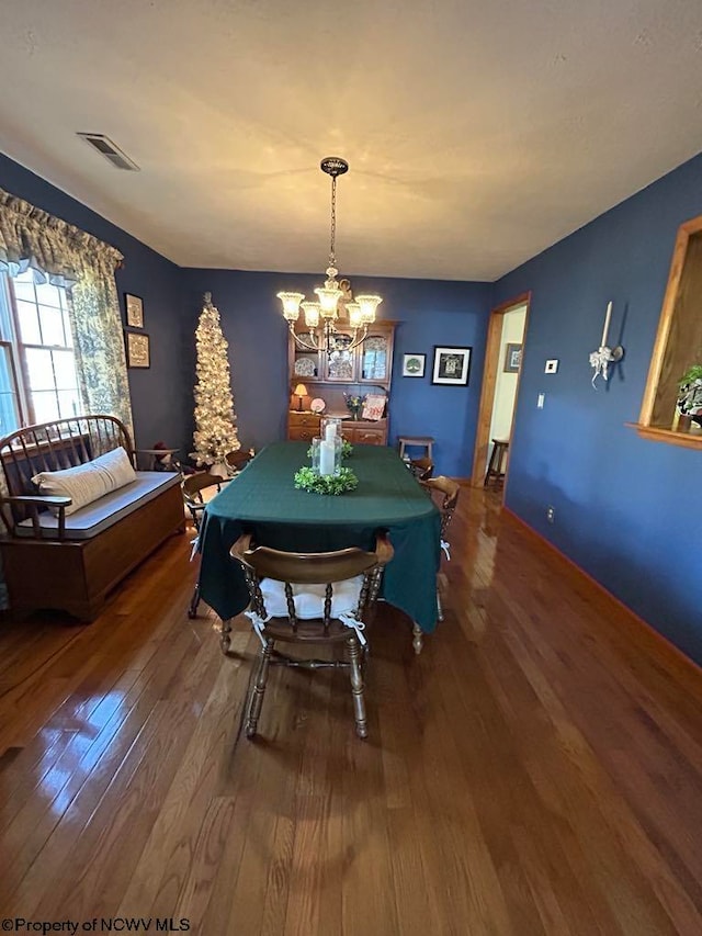 dining space with visible vents, a chandelier, and hardwood / wood-style floors