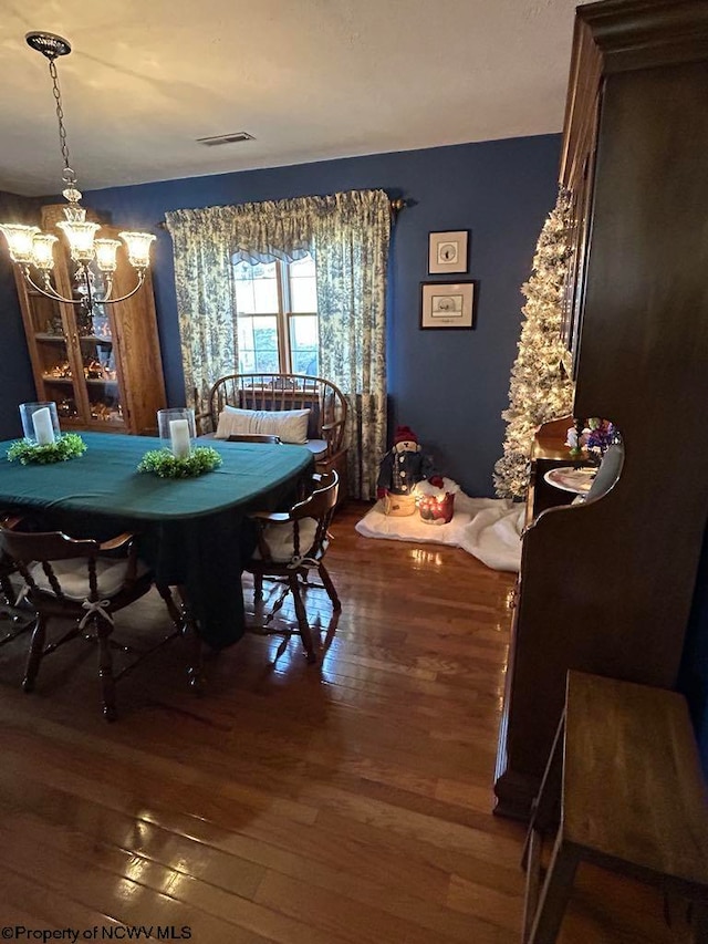 unfurnished dining area with hardwood / wood-style flooring, visible vents, and a notable chandelier