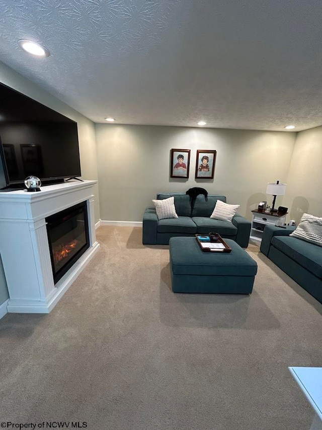 living area with baseboards, a glass covered fireplace, carpet, a textured ceiling, and recessed lighting