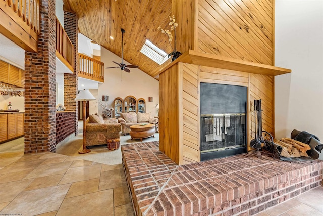 interior space with a skylight, a ceiling fan, a glass covered fireplace, wood ceiling, and high vaulted ceiling