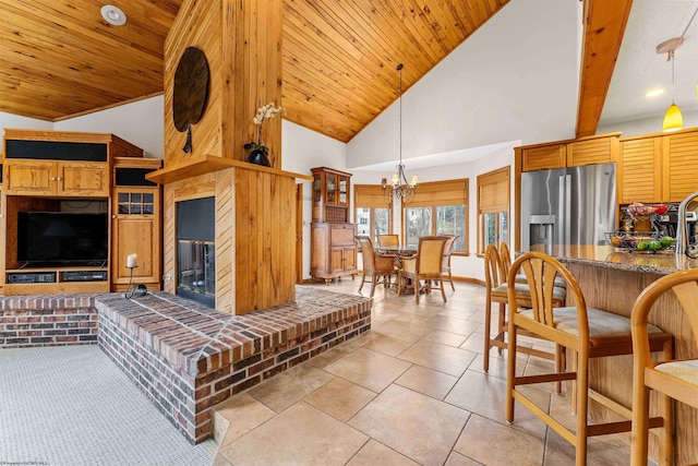 living room featuring a fireplace, an inviting chandelier, wood ceiling, light tile patterned flooring, and high vaulted ceiling