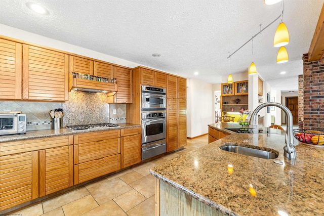 kitchen with decorative light fixtures, a warming drawer, stainless steel appliances, decorative backsplash, and a sink