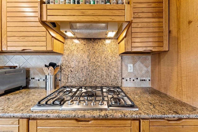 kitchen with stainless steel gas cooktop, ventilation hood, backsplash, and a toaster