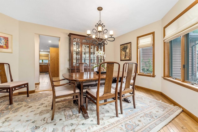 dining room with light wood-style floors, baseboards, and an inviting chandelier