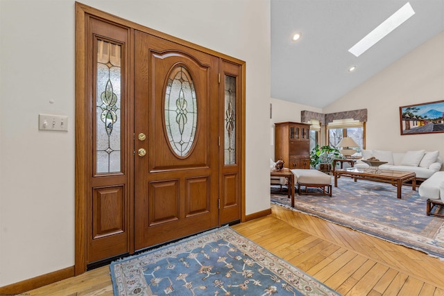 entrance foyer with light wood-type flooring, a skylight, high vaulted ceiling, and baseboards