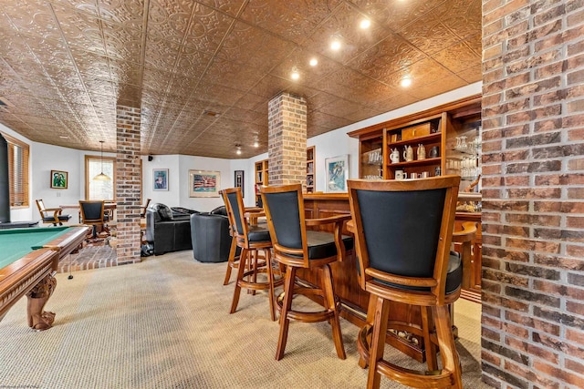 bar with brick wall, a dry bar, carpet floors, and decorative columns