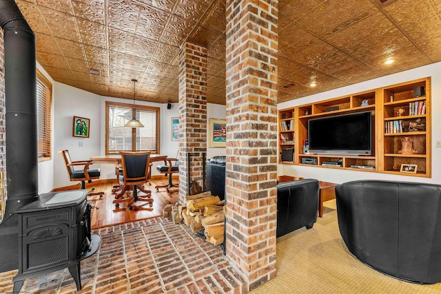 living room with baseboards, built in features, an ornate ceiling, wood finished floors, and a wood stove