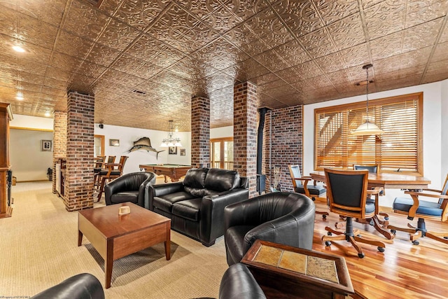 living room featuring an ornate ceiling, visible vents, light wood-type flooring, a wood stove, and ornate columns