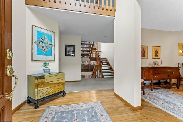 entryway with a textured ceiling, stairway, baseboards, and hardwood / wood-style flooring