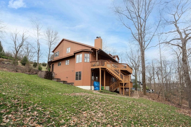 back of property with stairs, a chimney, a deck, and a lawn