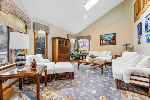 living room with high vaulted ceiling, a skylight, wood finished floors, and a healthy amount of sunlight