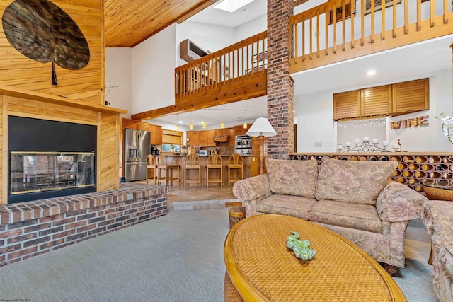 carpeted living room with a glass covered fireplace, a towering ceiling, and a skylight