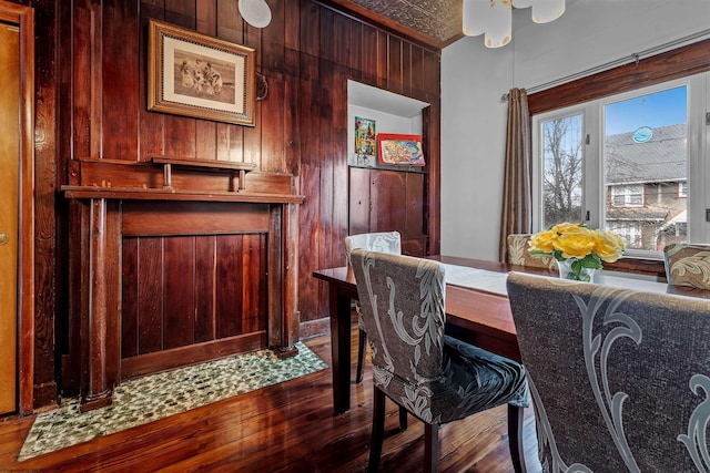 dining area with wood walls, dark wood-style flooring, and an ornate ceiling