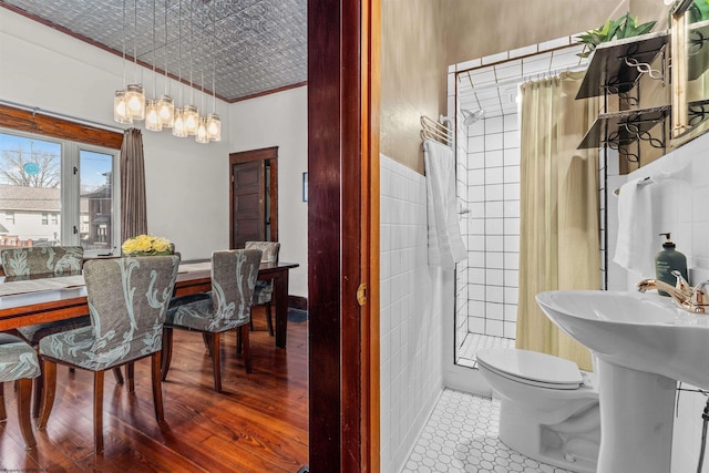 dining space featuring wood finished floors, an ornate ceiling, and tile walls