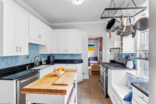 kitchen featuring white cabinetry, appliances with stainless steel finishes, wooden counters, and backsplash