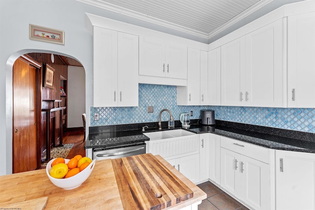 kitchen featuring arched walkways, tasteful backsplash, a sink, butcher block countertops, and dishwasher