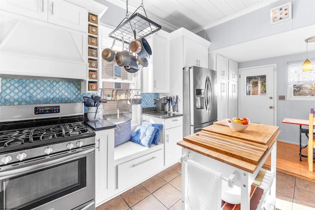 kitchen featuring custom exhaust hood, decorative backsplash, appliances with stainless steel finishes, ornamental molding, and white cabinetry