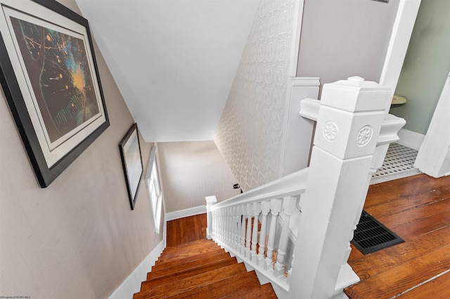 staircase featuring wood-type flooring, visible vents, and baseboards