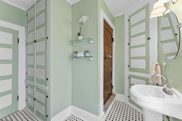 bathroom with ornamental molding, a sink, and baseboards