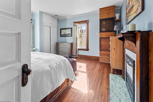 bedroom featuring ornamental molding, a closet, wood finished floors, and baseboards