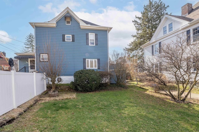 back of house featuring fence and a yard