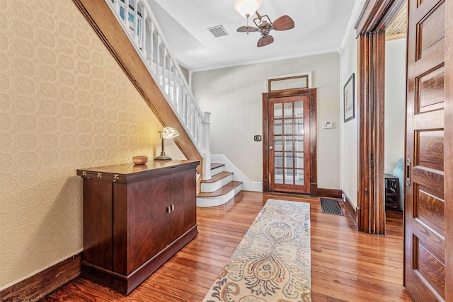 entryway featuring baseboards, visible vents, ornamental molding, hardwood / wood-style floors, and stairs