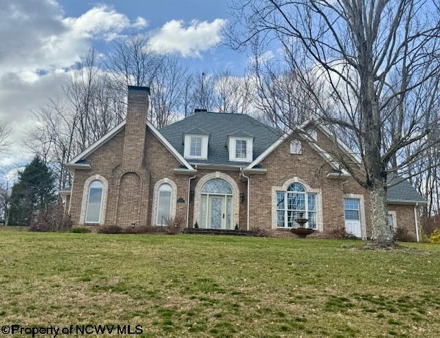 view of front of home featuring brick siding, a shingled roof, a chimney, and a front yard