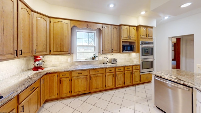 kitchen with tasteful backsplash, appliances with stainless steel finishes, recessed lighting, and light stone countertops