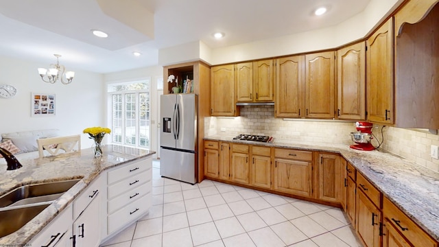 kitchen with light stone counters, a sink, appliances with stainless steel finishes, tasteful backsplash, and pendant lighting